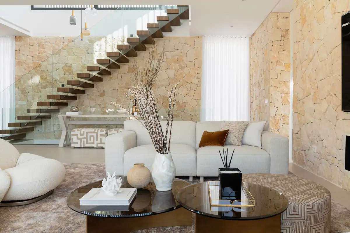 salon tonos neutros con escalera y paredes piedra