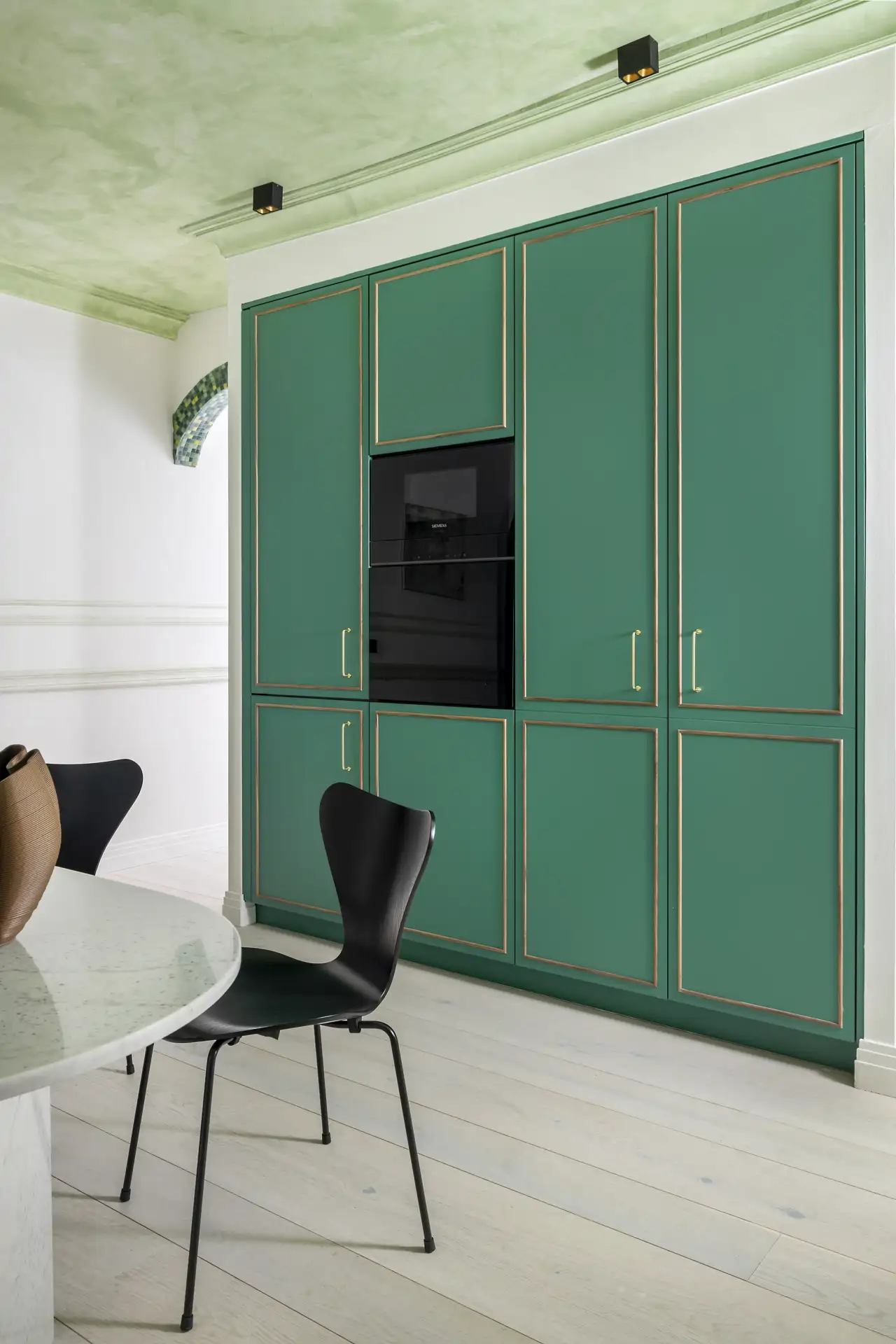 Una cocina en verde con detalles en dorado