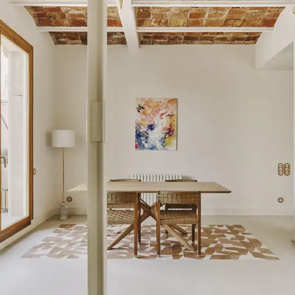 Las paredes blancas, los muebles de madera y los guiños a la arquitectura catalana guían la reforma de este piso en Barcelona, firmado por Andrea Arqués