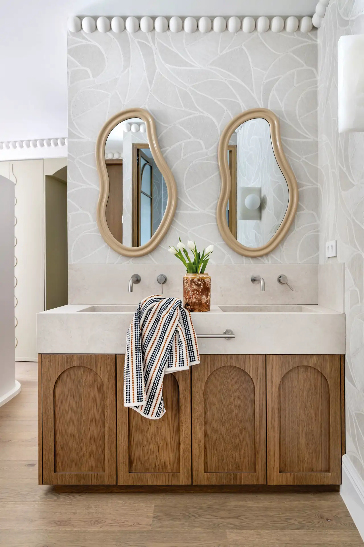 Baño con mueble de madera y espejos curvos