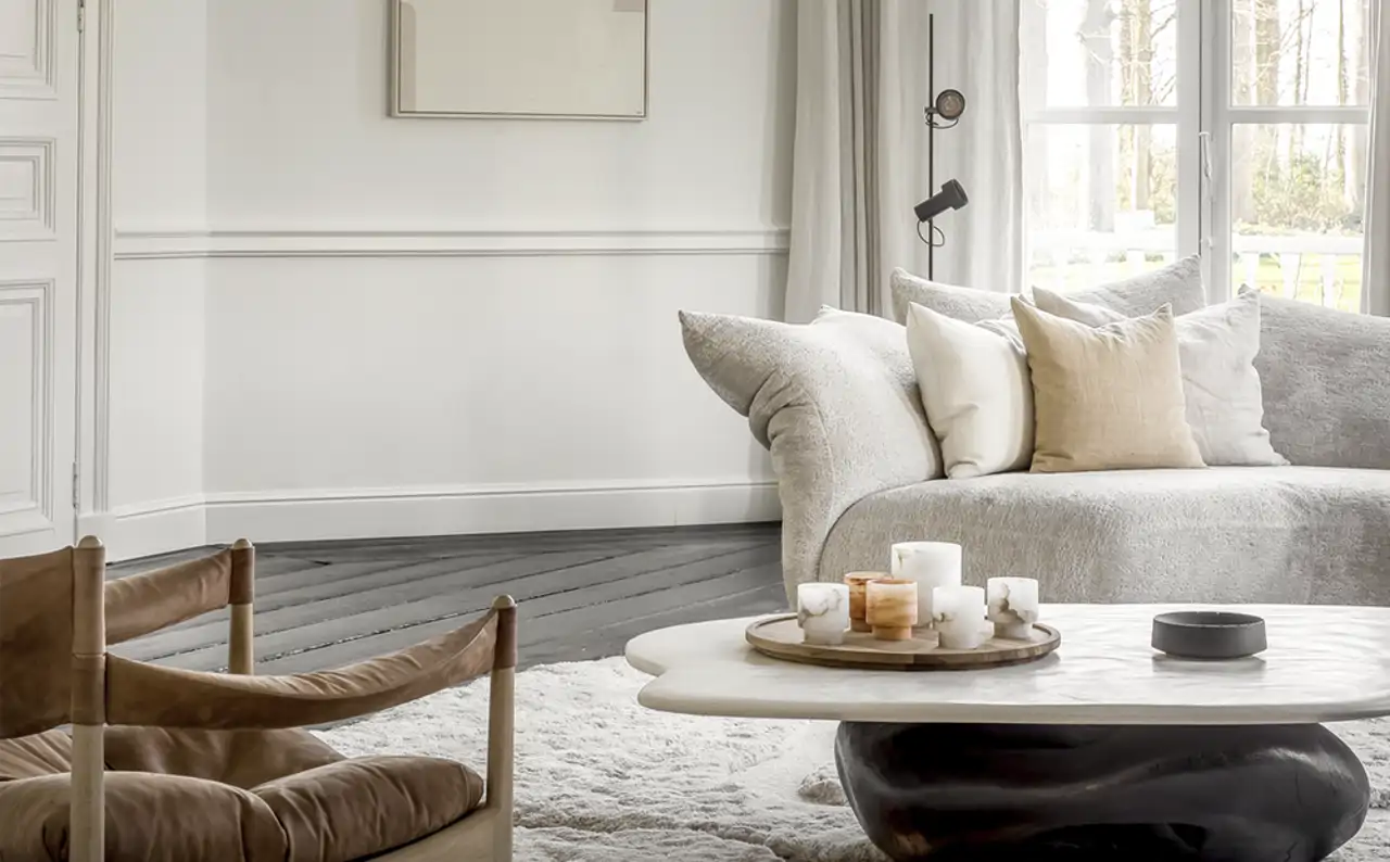 Salón en tonos blancos con textura, alfombra y butaca