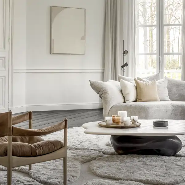 Salón en tonos blancos con textura, alfombra y butaca