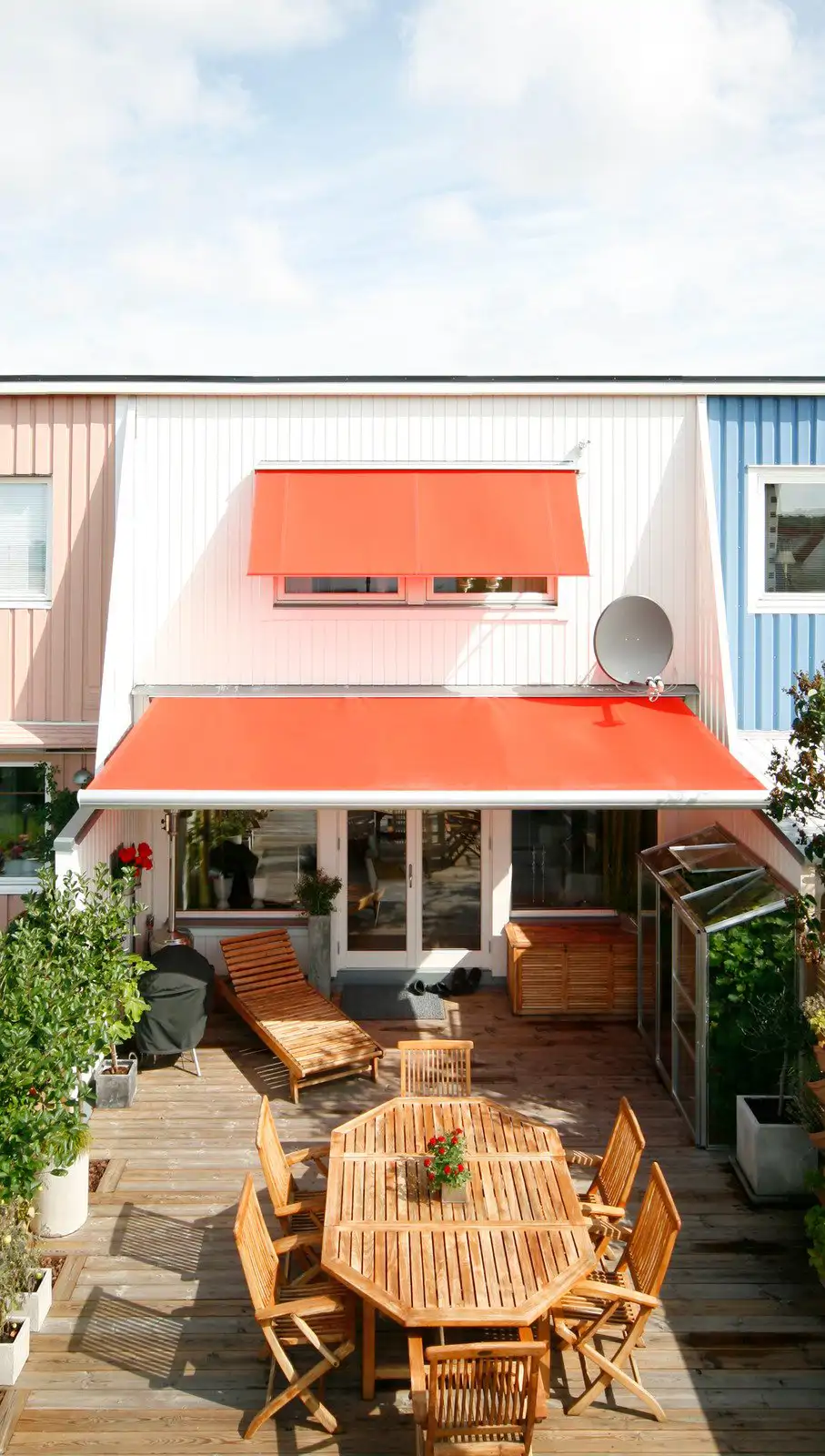 Terraza con mesa y sillas de madera y toldo naranja