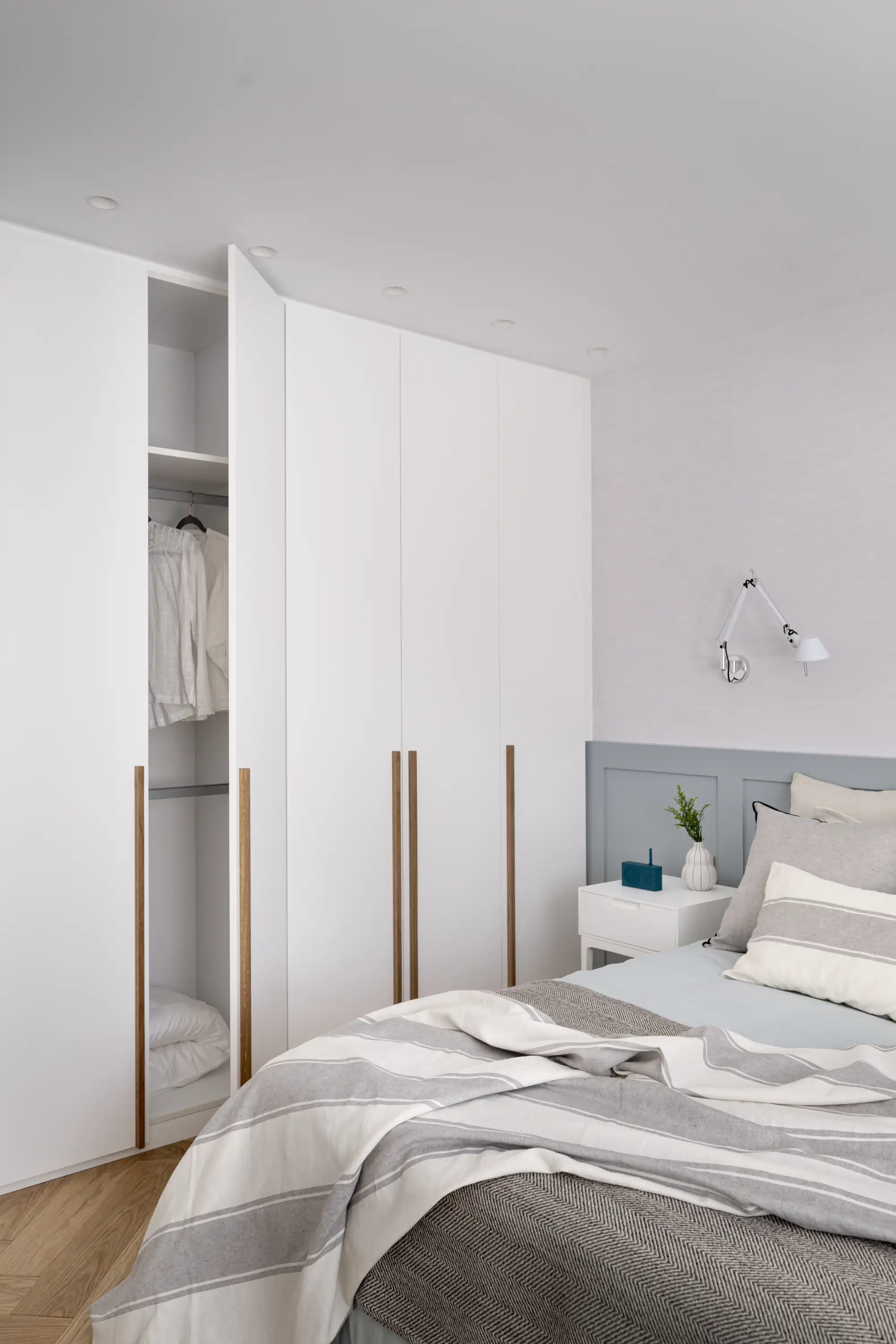 Un dormitorio gris y blanco con muebles blancos
