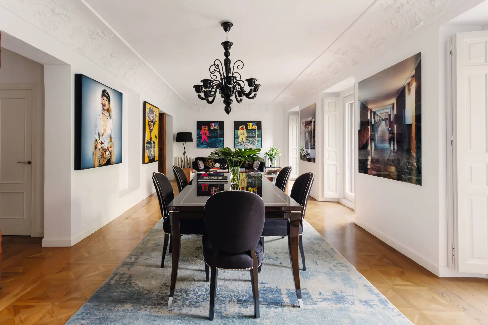 Comedor con muebles oscuros, cuadros y lámpara de araña