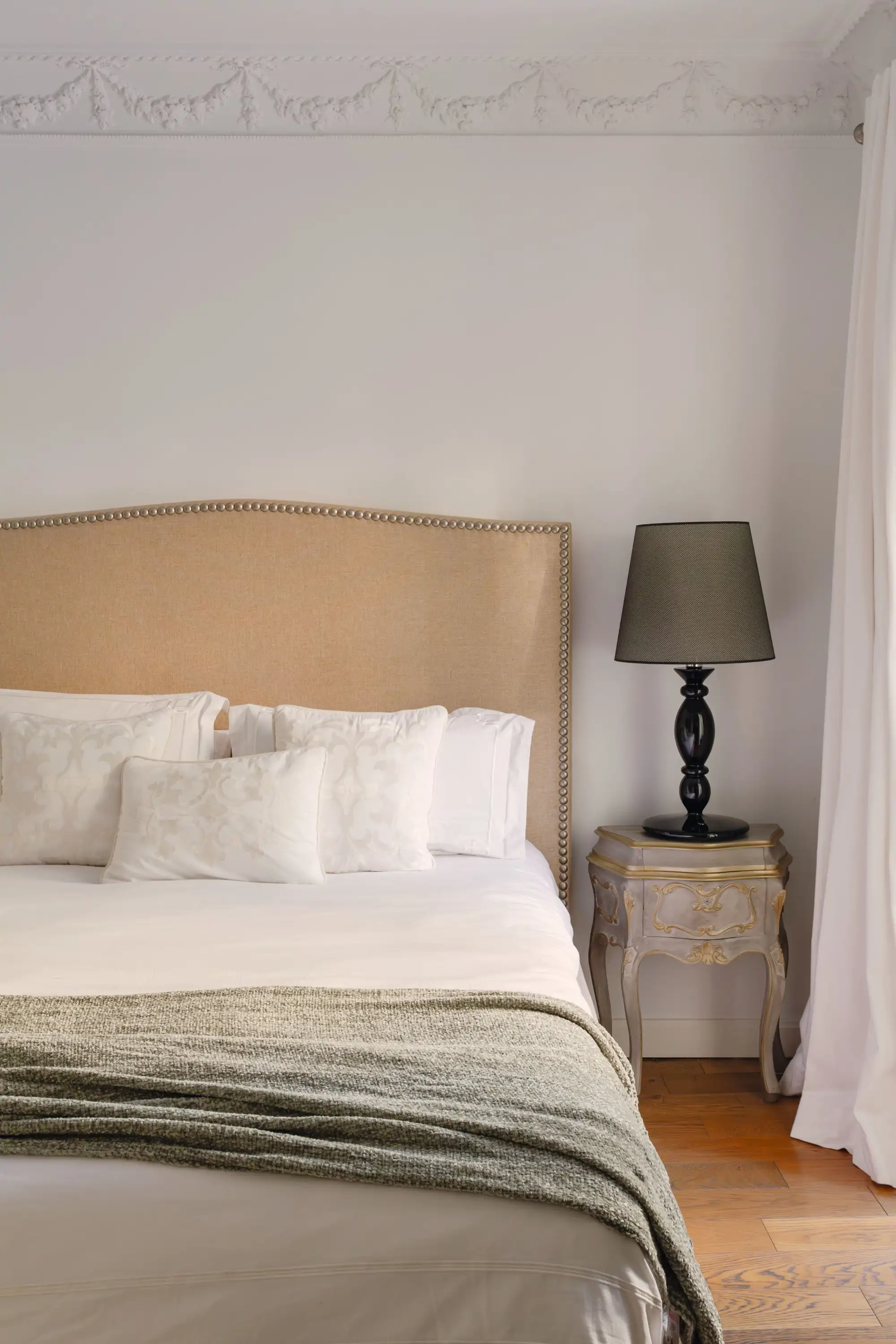 Dormitorio con mesita de noche clásica y cabecero crema