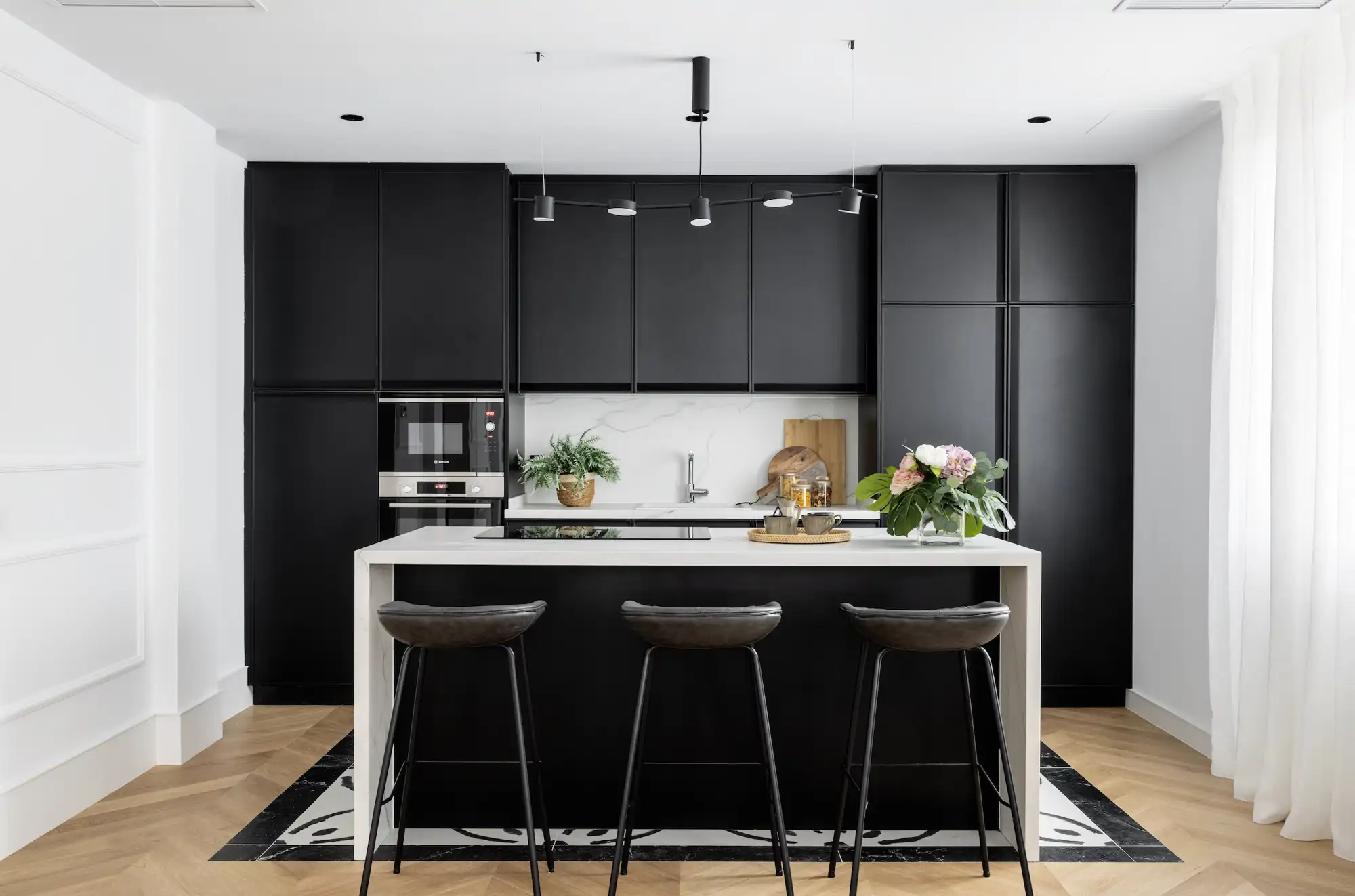 cocina negra con isla blanca y taburetes